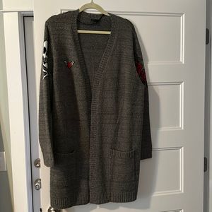 Torrid cardigan with skull and crossbones, heart with wings and roses.